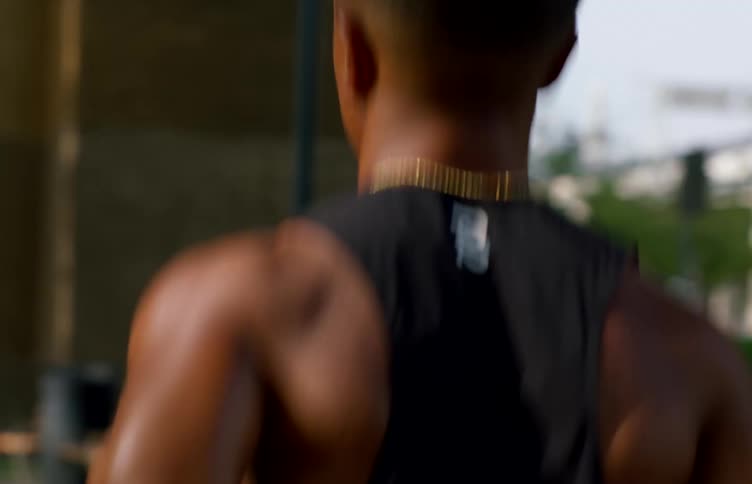 A man is running outdoors under an overpass wearing athletic clothing as part of a cardio workout