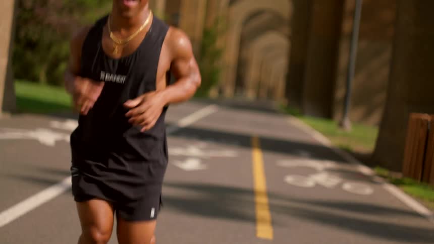 A man laughs joyfully while running on a sunlit path clearly enjoying the moment and his fitness routine