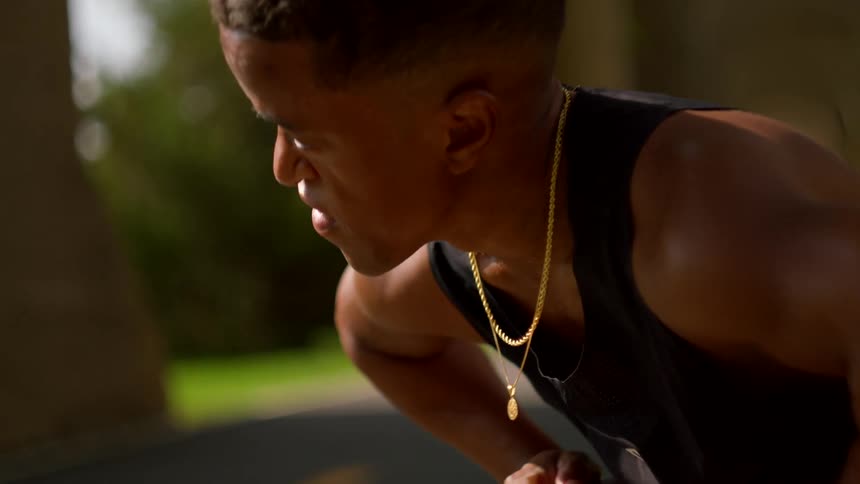 A man bends over catching his breath after a run visibly exhausted in the daylight