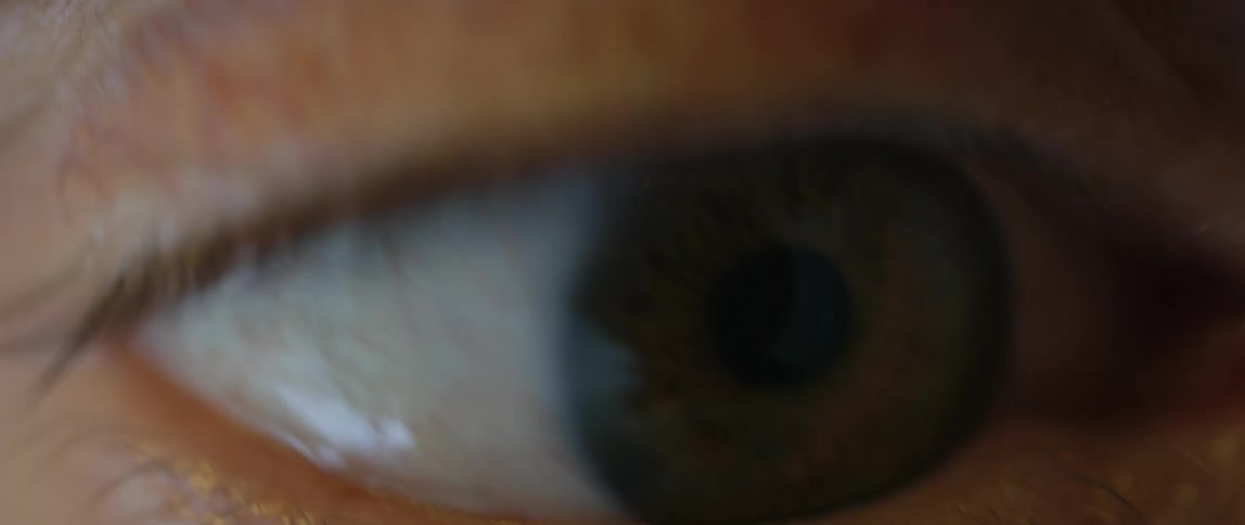 Extreme closeup of an eye moving with dramatic lighting and reflections