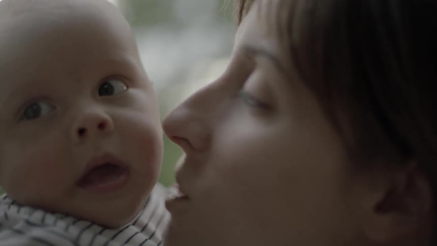 A woman holding a baby and kissing it on the cheek and smiling