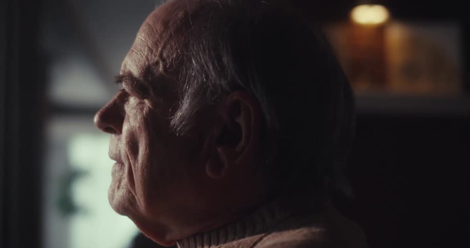 A man is sitting at a table and leaning forward looking worried