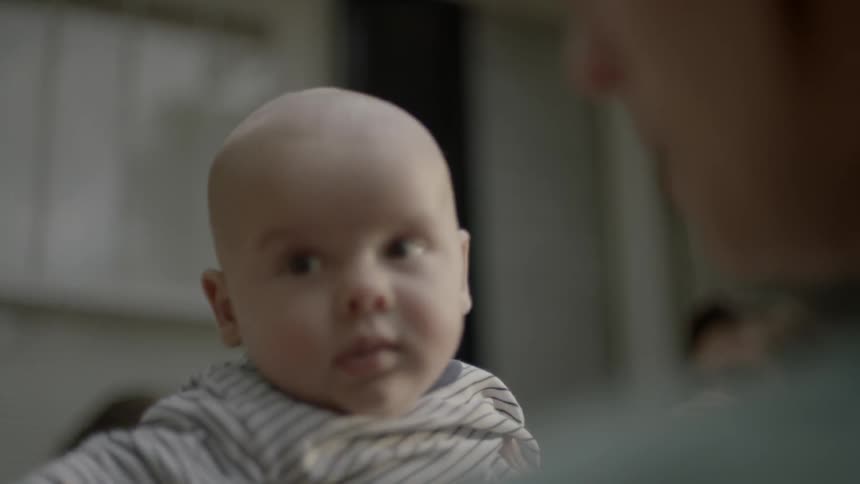 Man holding a baby that is waving its arms