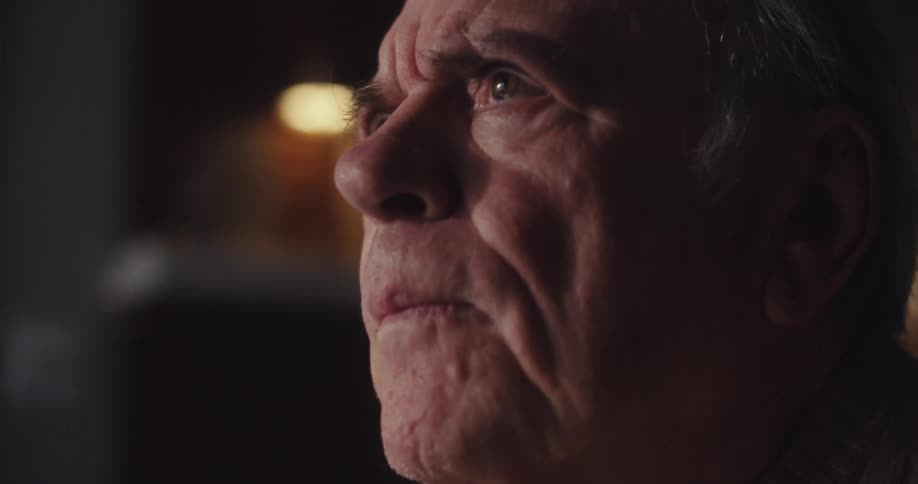 An elderly man pauses thoughtfully while writing an email then smiles gently