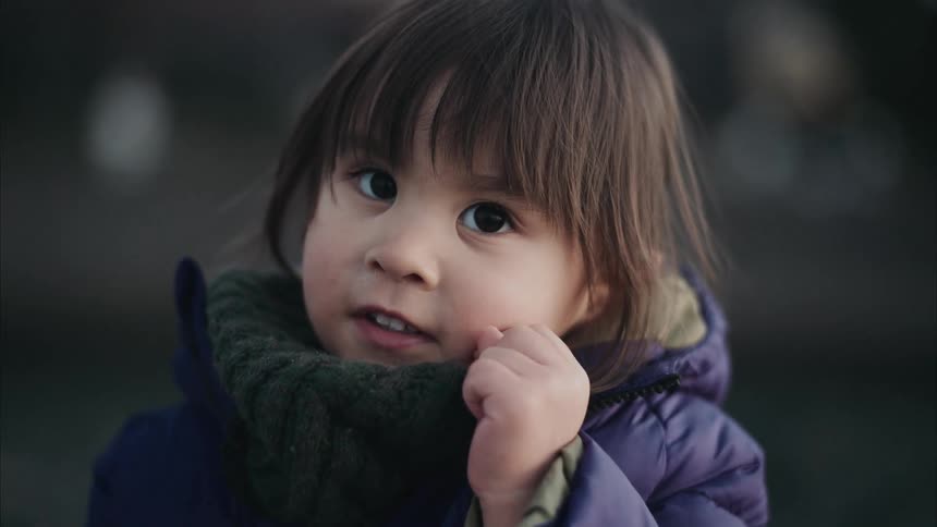 A bundled child looks offcamera making a playful gesture