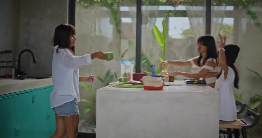 A mother and her kids share drinks at a kitchen island