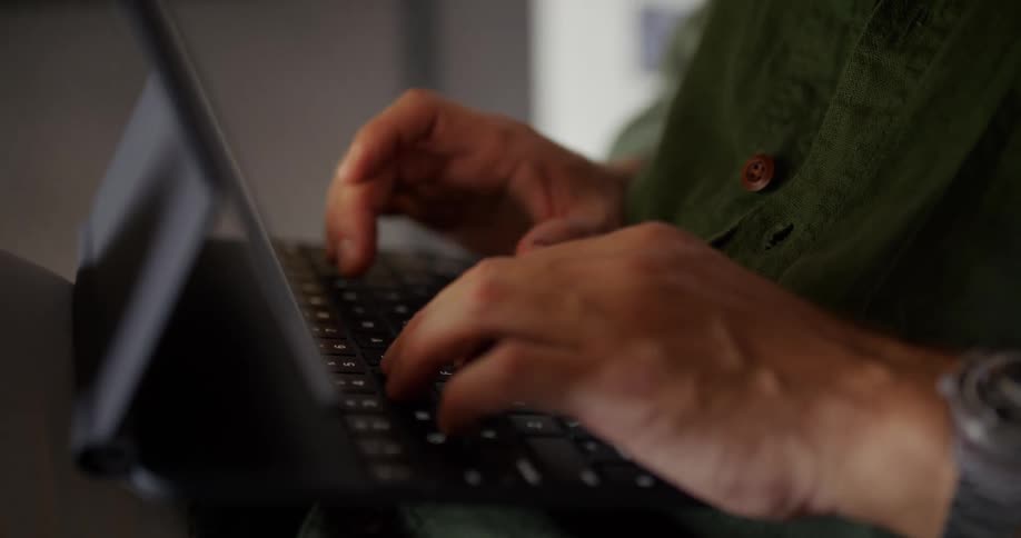 A man is typing on a keyboard with his tablet