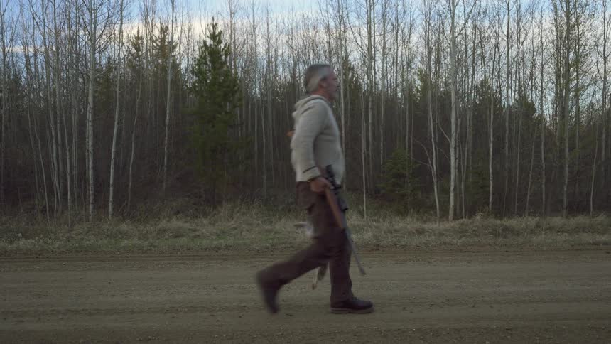 The hunter is walking with dead bunnies in his hand