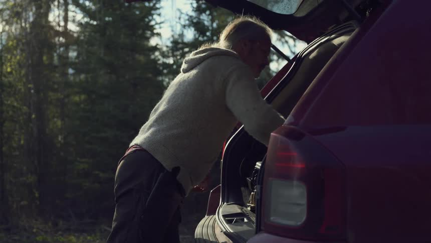 Hunter in the wildernes putting a dead rabbit in back of his car