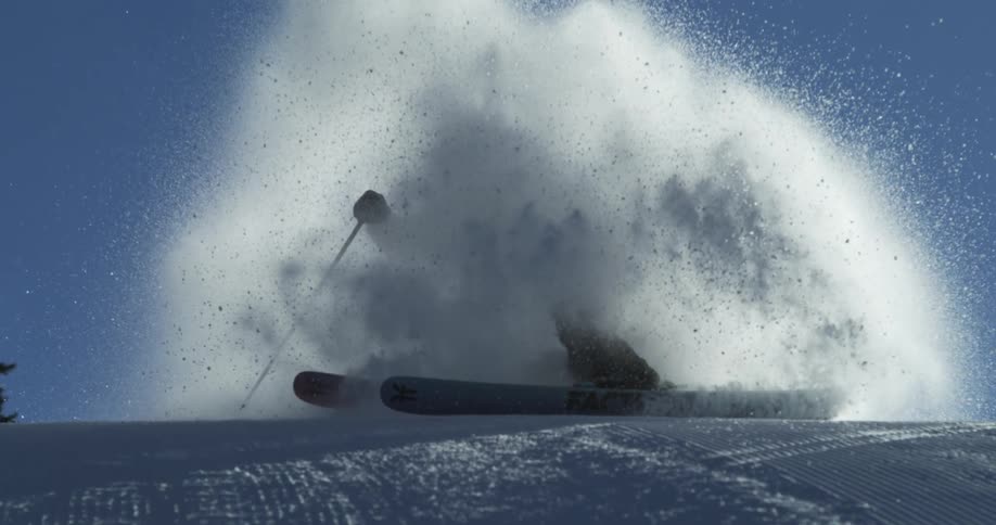 A person skiing on the slop gives throws off a huge pile of snow