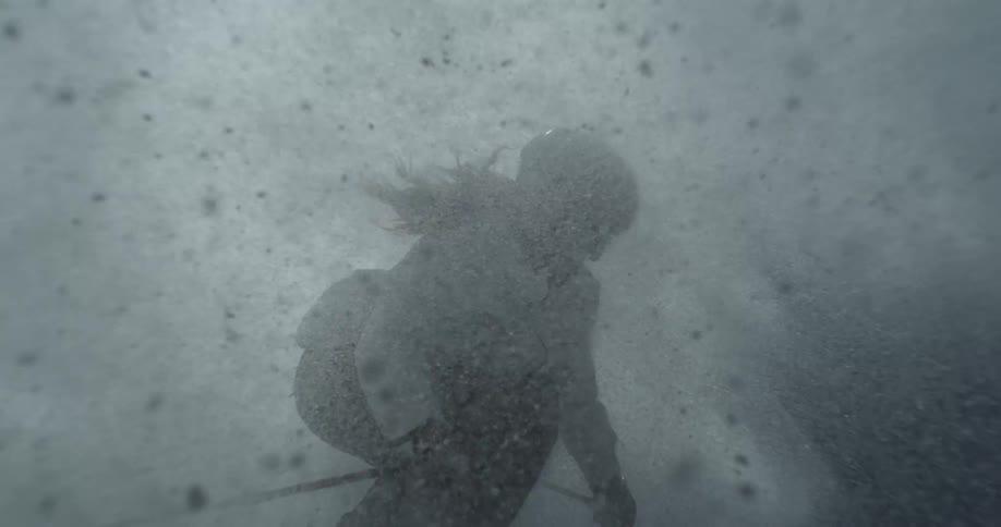 A skier skis through a thick spray of snow under bright sunlight