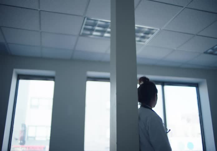 Nurse leaning against a pillar in a hospital room
