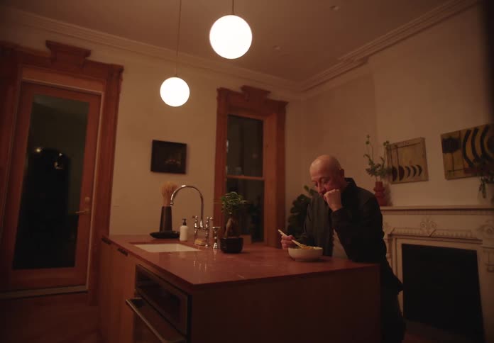 Thoughtful man sitting at the kitchen sink with a bowl in front of him