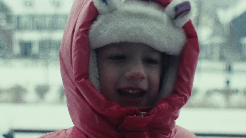 Little girl in hoodie playing with snowballs