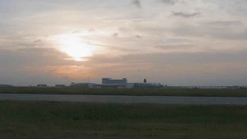 A large building is in the distance at sunset