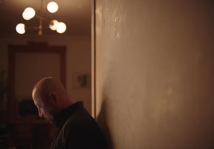 A man is leaning against the wall in the hall