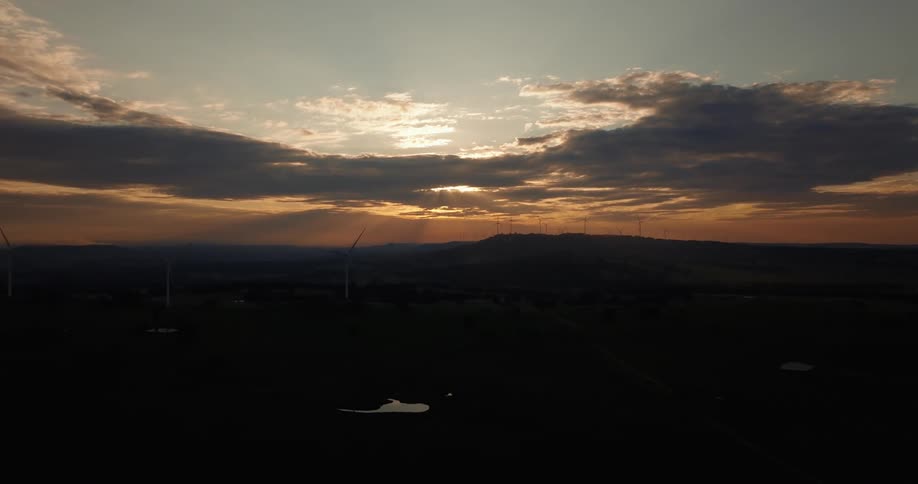 Windmills on a hill on the horizon at sunset