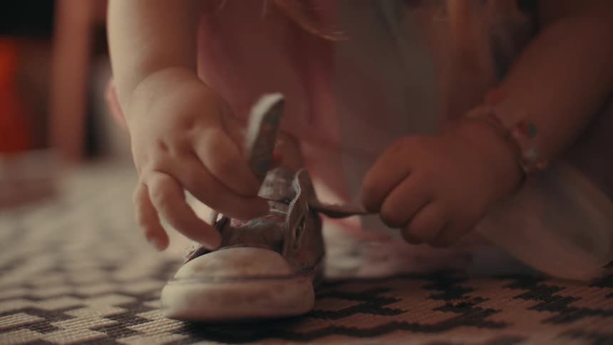 A child wearing a wristwatch buckles her shoe and walks out