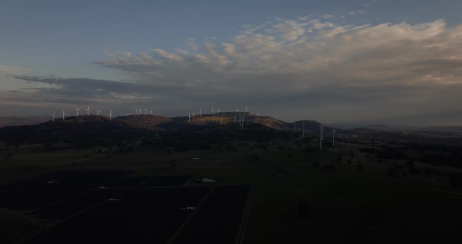 Wind turbines line the horizon at sunset