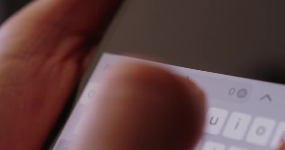Fingers type the word budget on a brightly illuminated smartphone keyboard