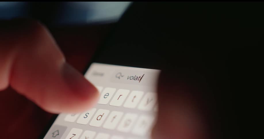 Fingers type on a brightly illuminated smartphone keyboard in a dimly lit area