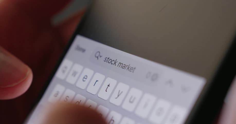The person searches stock market on a cell phone