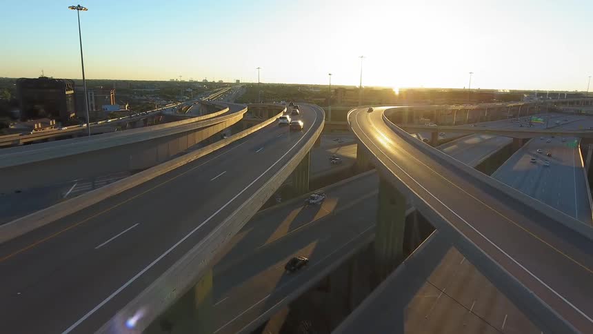 Cars drive on a highway system in a city