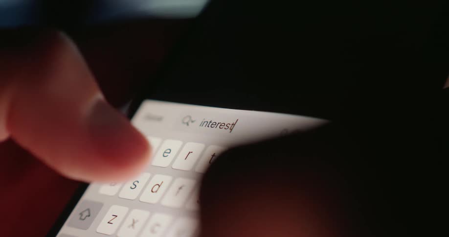 A person typing the word interest on their phone