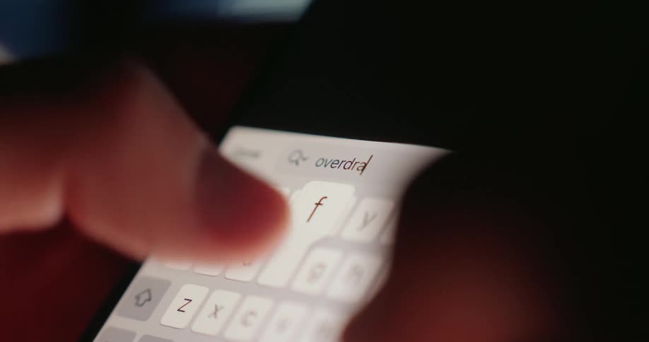 A person types the word overdraft on their phone