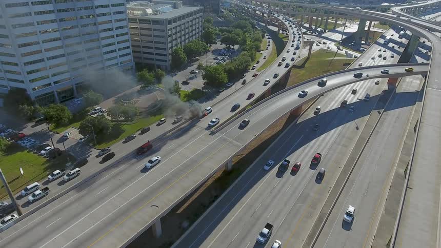 Cars drive on a highway system in a city