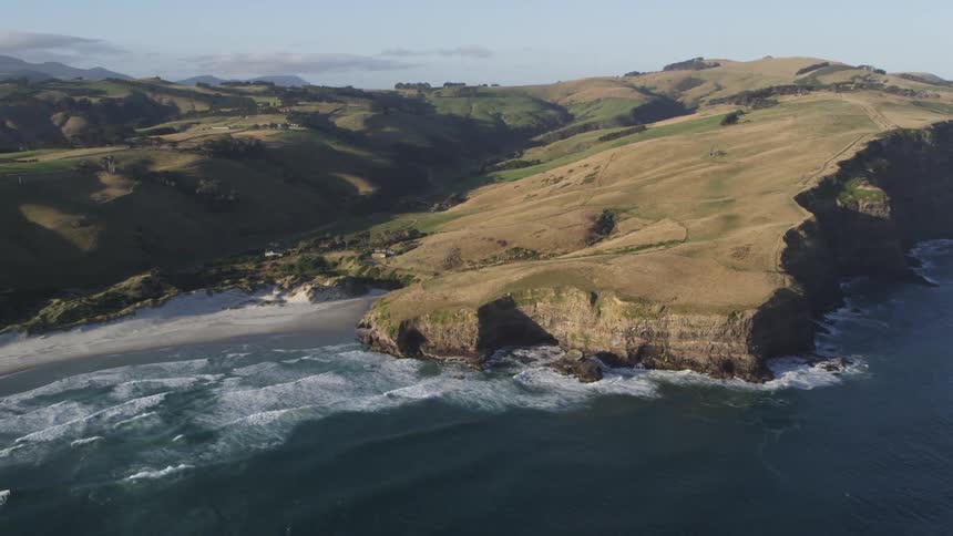 Waves crash against the beach on hilly piece of land