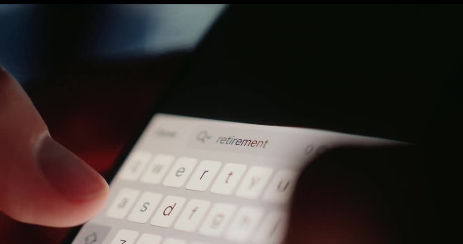 A closeup shot shows fingers typing the word retirement into a search bar on a smartphone screen
