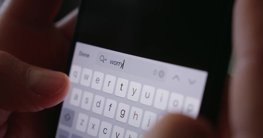 A person types the word worry into a smartphone search bar in a closeup shot