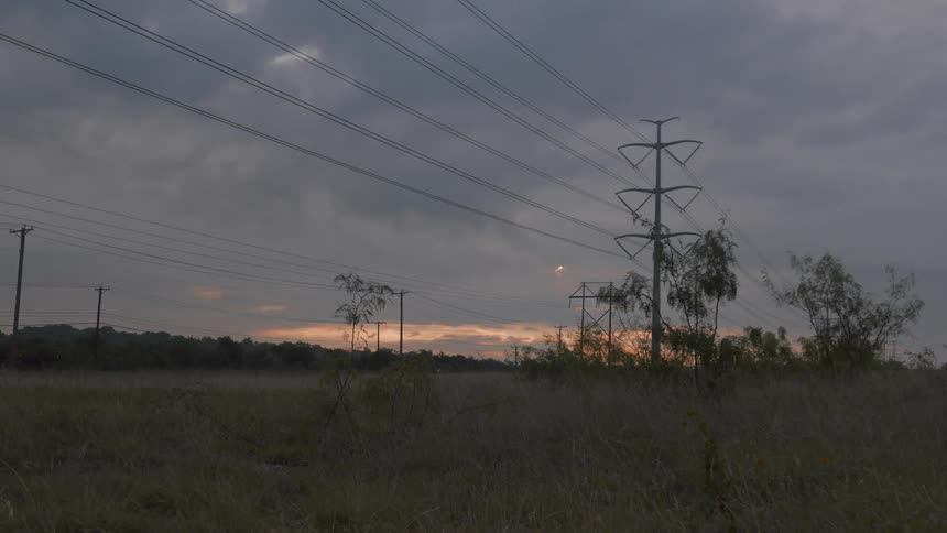 The clouds pass fast over the power lines and road