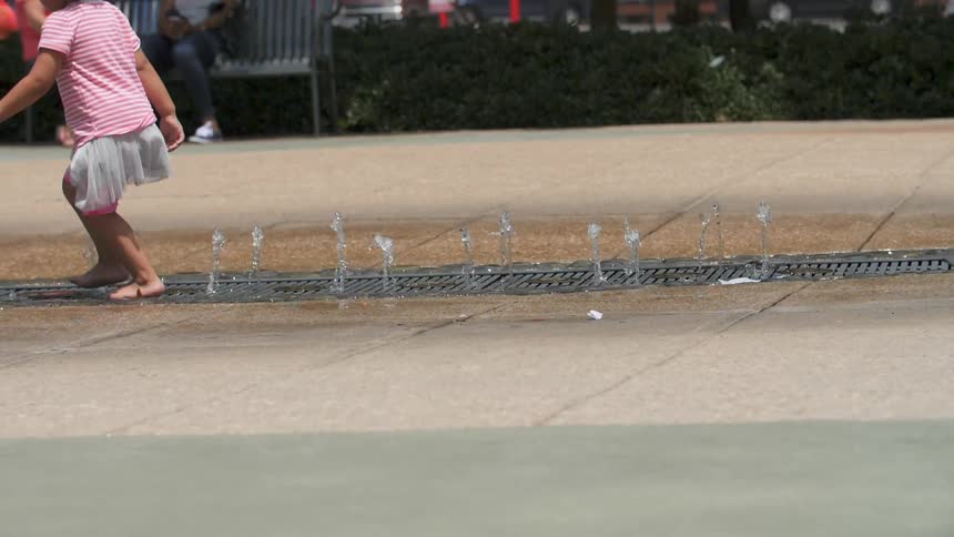 A child is walking in the fountain on the ground