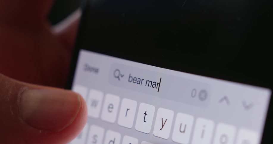 A persons finger types bear market on a smartphone