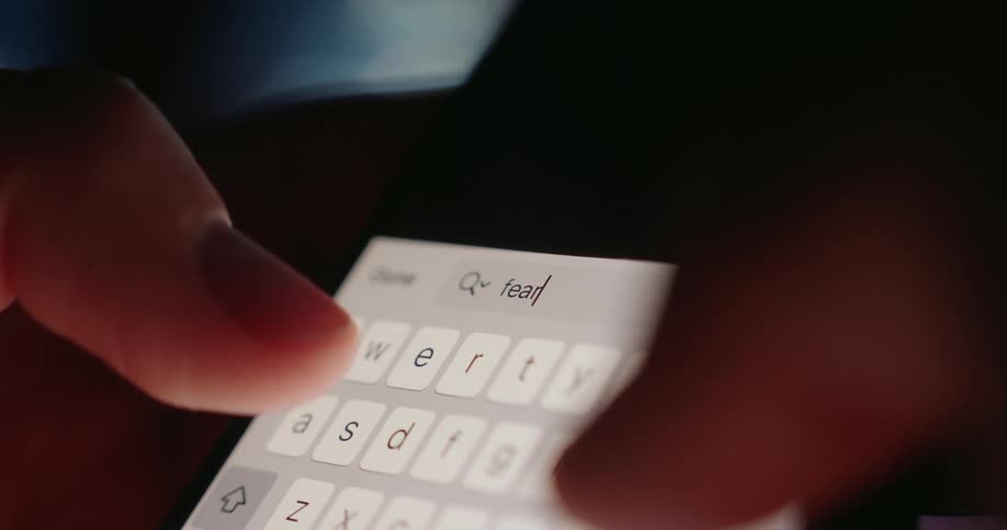 The person is typing the word fear into their cell phone search engine