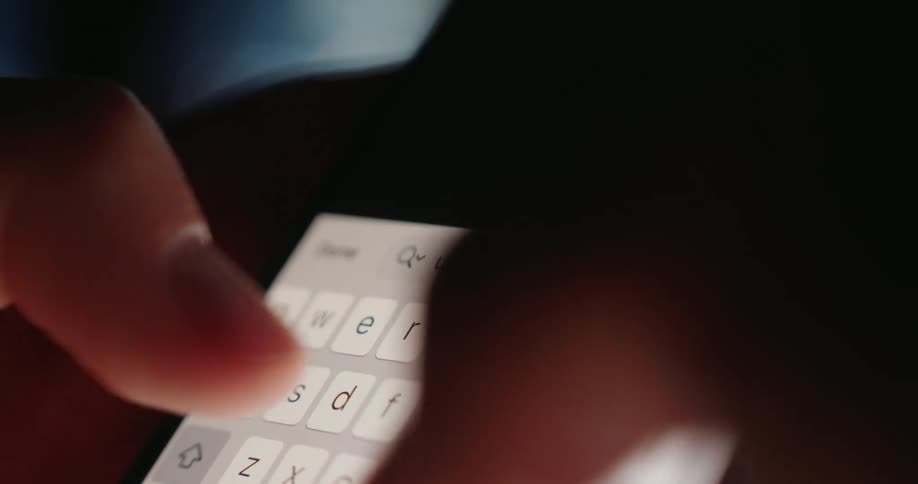 A persons fingers typing quickly on a whitekeyed keyboard on a cell phone