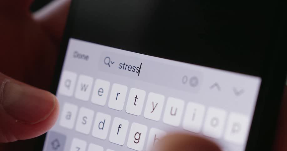 A persons finger types the word stress on a smartphone