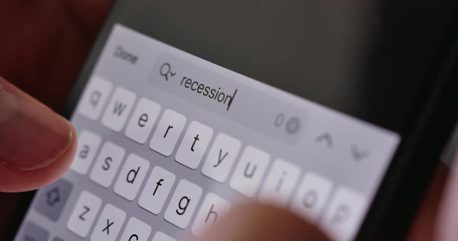 A persons finger holding a smartphone types recession on the device