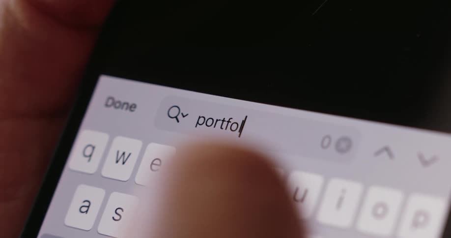 A persons finger typing on a cell phone screen on white keys with black letters
