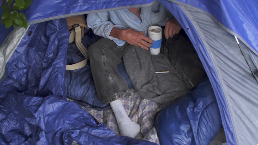 A person picks up a cigarette in a tent