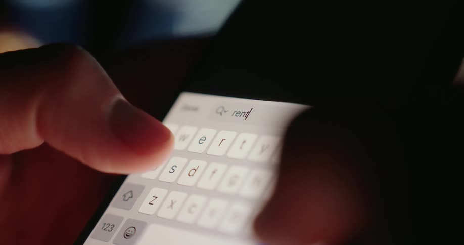 A person typing the word rent on their phone