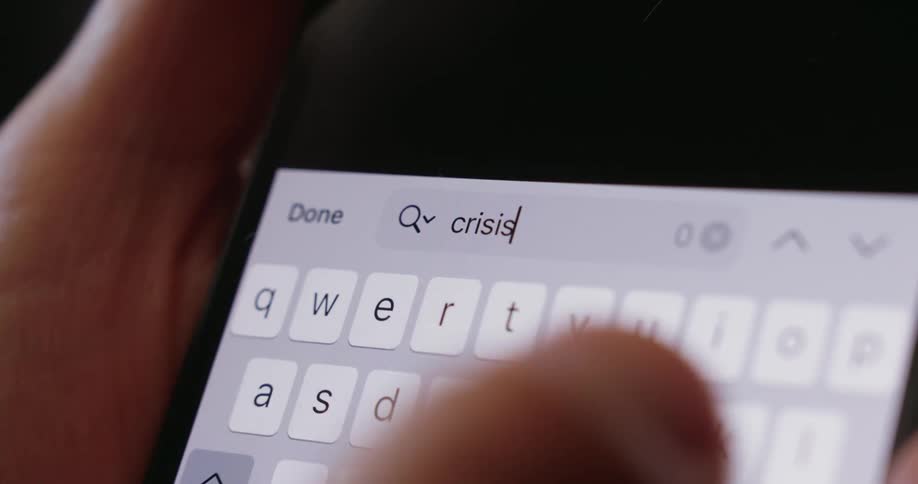 Fingers type on a brightly illuminated smartphone keyboard in a dimly lit area
