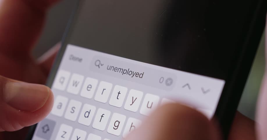A person holding a smartphone types unemployment on it