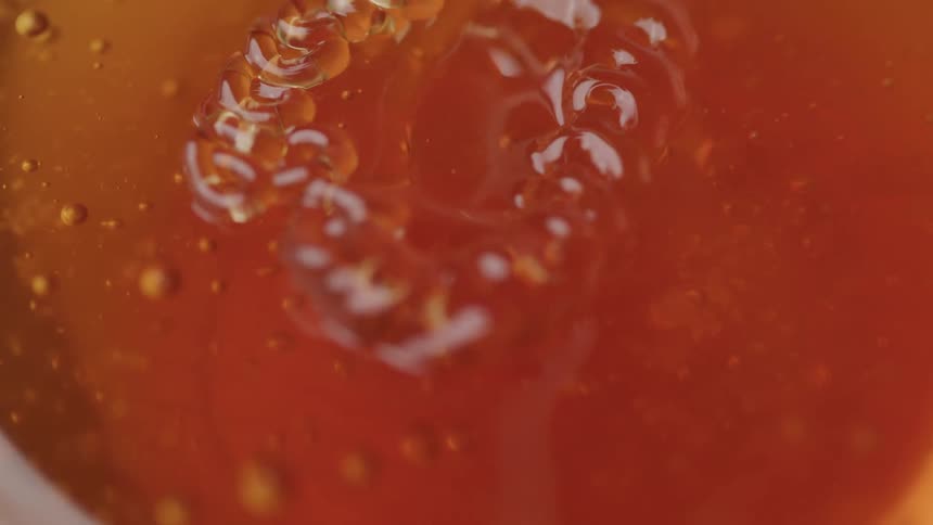 Macro shot of bubbles and a coiled structure in amber liquid creating an abstract visual