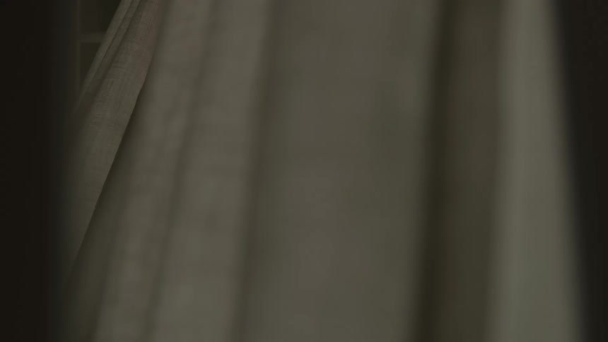 Curtains flowing from an open window in a dim lit room