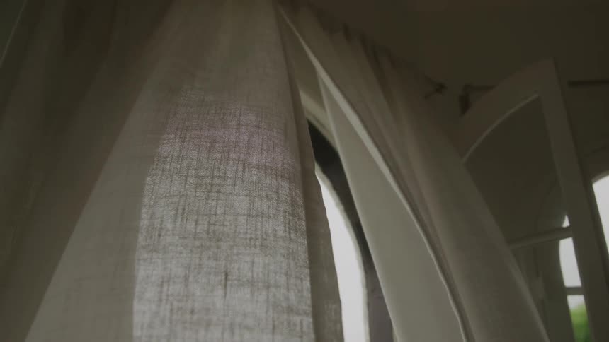 The white curtain blows in the wind