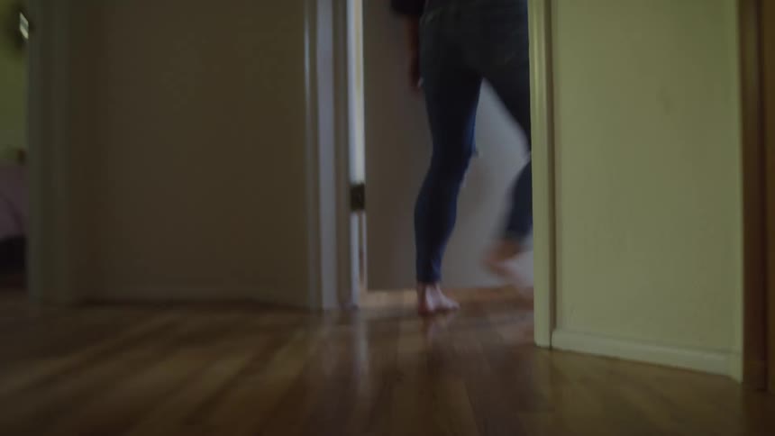 Legs of a woman walking down the hallway entering a room and closing the door