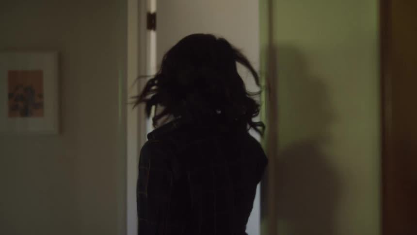 Woman walking down a hallway and entering a room looking dejected